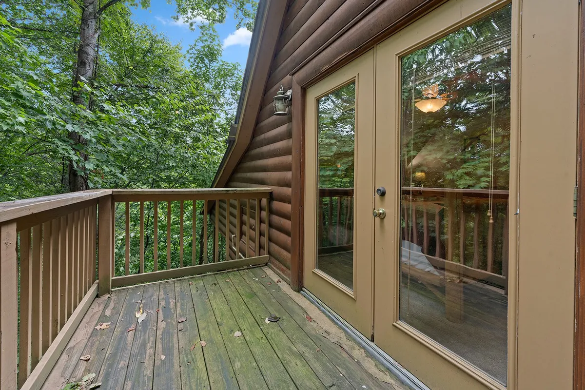 A peaceful wooden deck with double glass doors opening to greenery, inviting guests to step outside. The space suggests a seamless indoor-outdoor flow, perfect for morning coffee, quiet conversation, or evening get-togethers.
