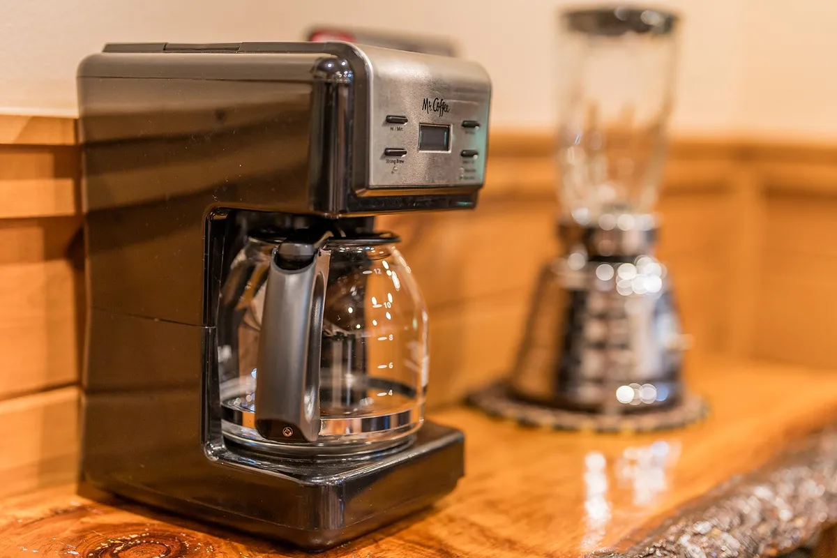 A close-up of the kitchen's coffee maker and blender on the countertop, suggesting the ease of brewing fresh coffee to enjoy on the balcony or porch.