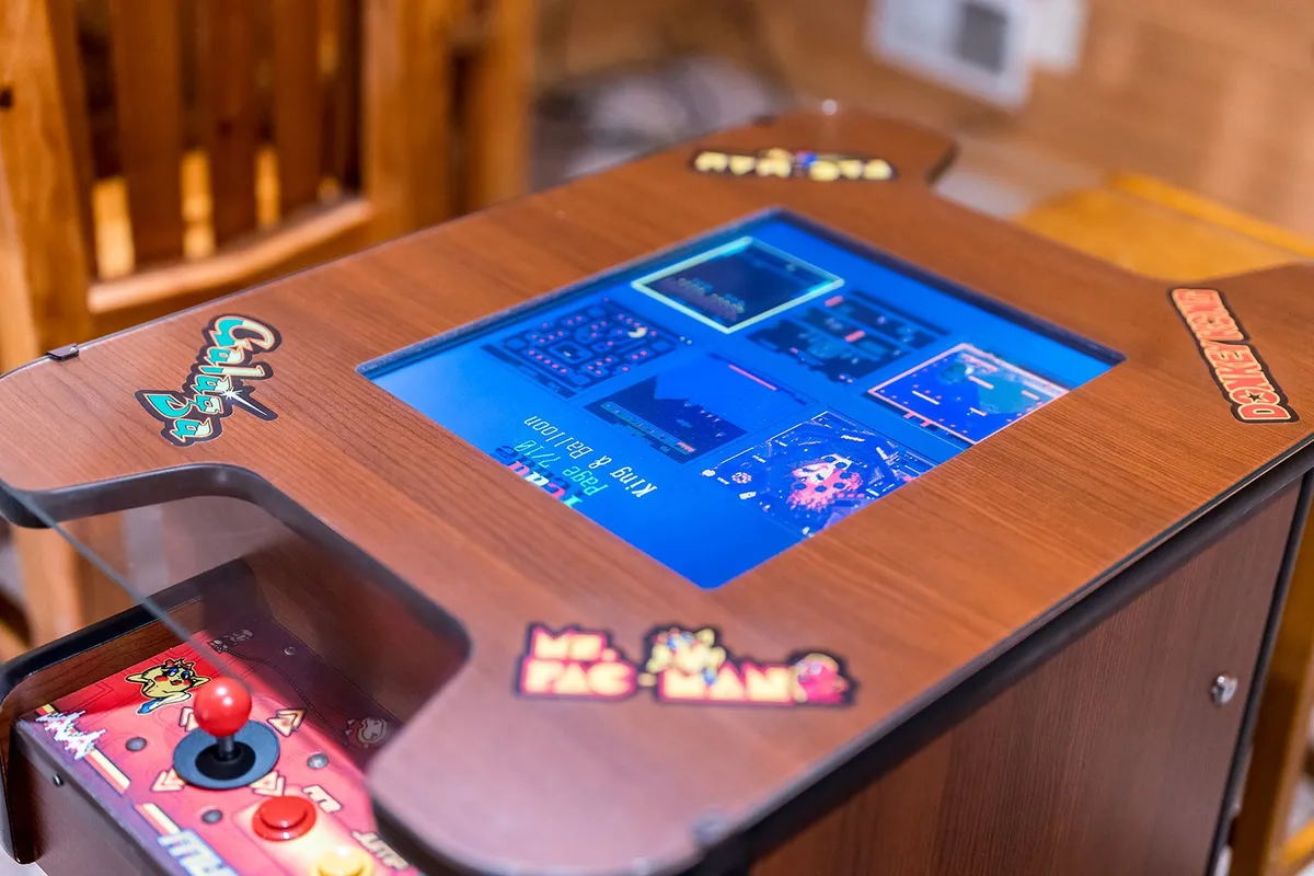 A close-up of a retro arcade game machine with vibrant graphics and an inviting control panel, set in a playful loft environment. The setup evokes both nostalgia and excitement.