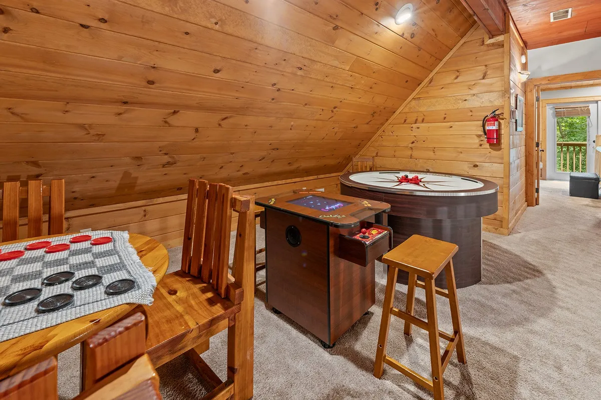 A bright, playful interior featuring a wooden dining table and a dedicated game table with stools, set in a relaxed and welcoming atmosphere. This space is perfect for family game nights and casual gatherings after an action-packed day.