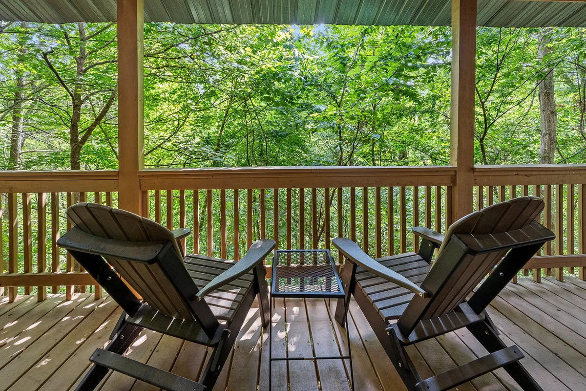 A peaceful wooden deck with two Adirondack chairs overlooking vibrant greenery, offering a tranquil spot to relax and unwind after a day of exploring local attractions and theme parks.
